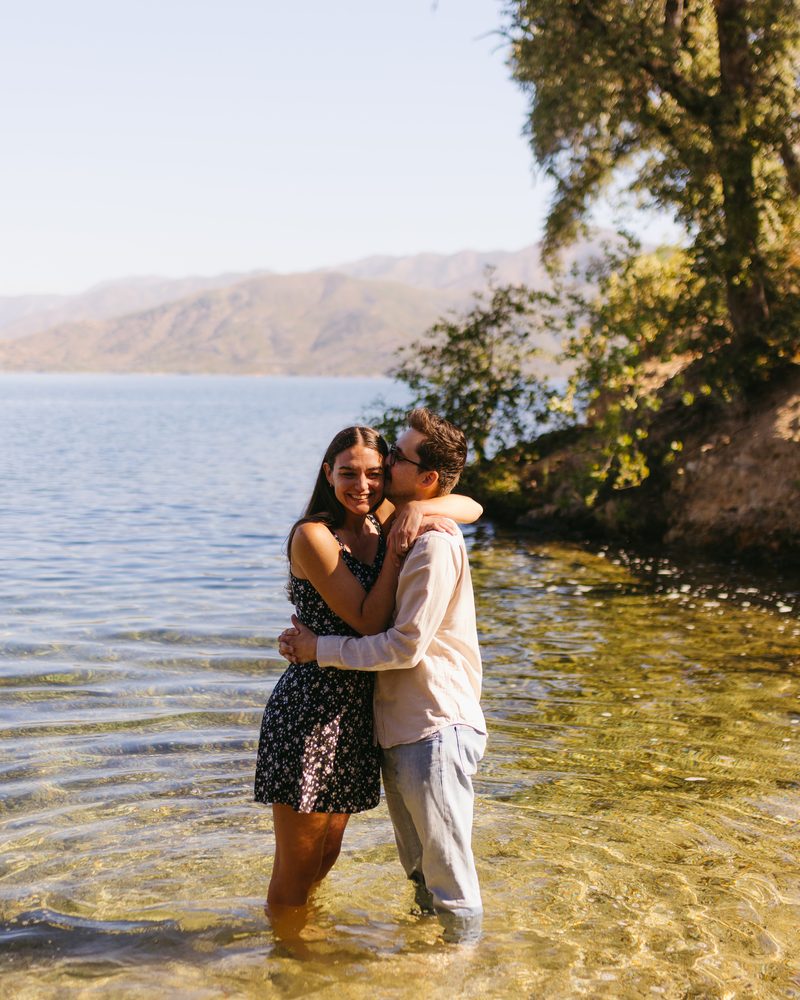 Andrea and Alex holding each other, standing in the shallows of the lake